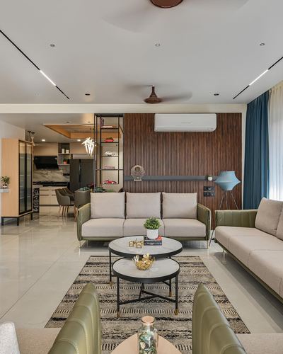 Living room with olive velvet sofas, round nested coffee tables and a fluted wood accent wall.