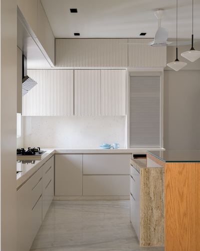 L-shaped kitchen with fluted white cabinetry, stone backsplash, and a wood-and-stone island
