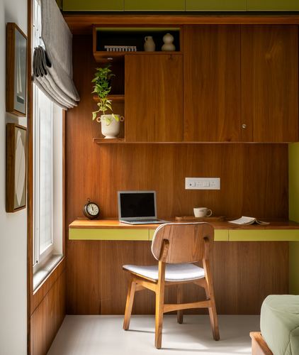 Wood-panelled study nook with desk, laptop, and wooden chair beside a curtained window