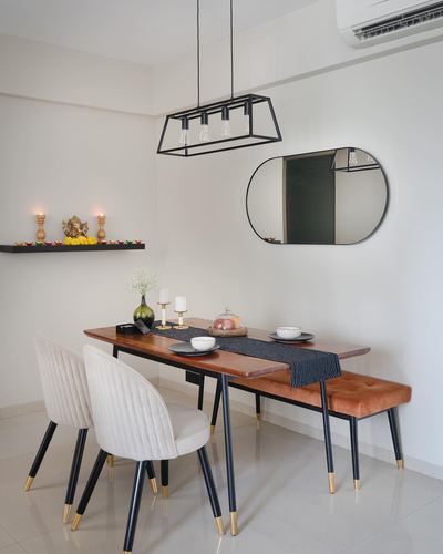 Dining table with cream chairs and rust velvet bench under black pendant and oval mirror