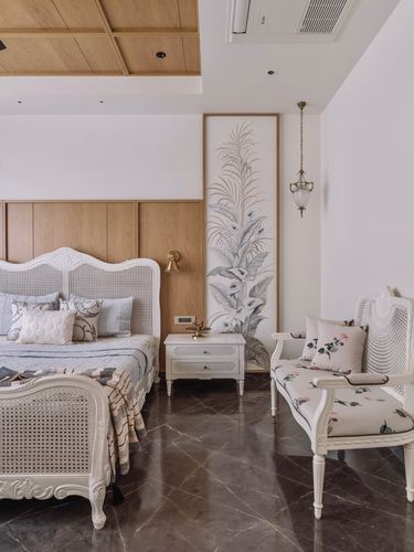 White cane-framed bed and matching settee in bedroom with dark marble floor and botanical mural