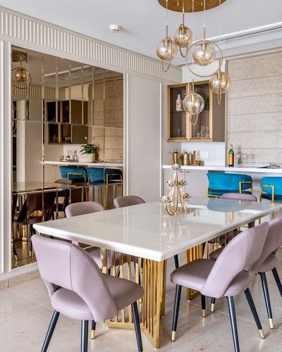 Dining room with marble table, gold legs, blush chairs, mirrored bar wall and cluster pendant lighting