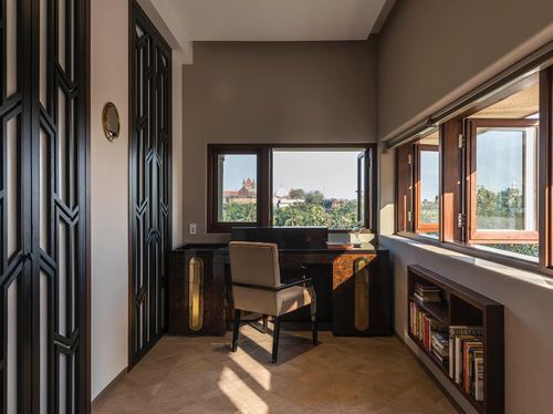 Art deco study nook with black geometric doors, desk, and window overlooking greenery in Mumbai home