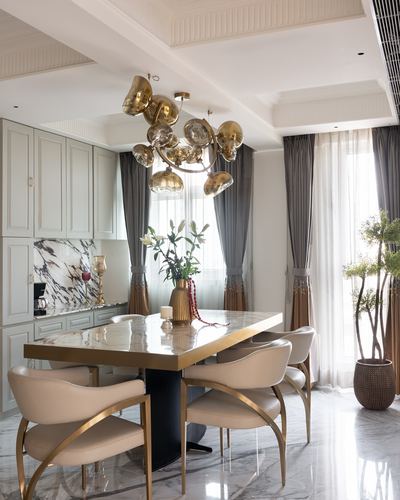 Dining room with marble table, gold-trimmed chairs and brass bubble chandelier