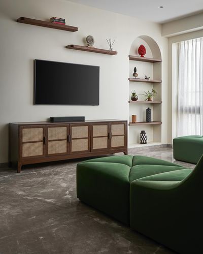 Living room with cane TV console, arched shelving niche, and green velvet sectional sofa