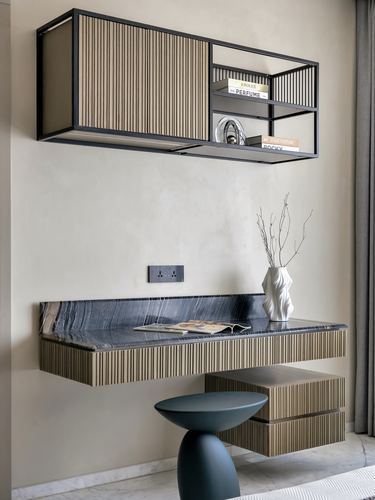 Floating fluted wood console with dark stone top under a black-framed wall shelf