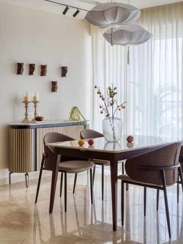 Dining table with cocoon pendant lights, fluted sideboard, and sheer curtains in a sunlit room