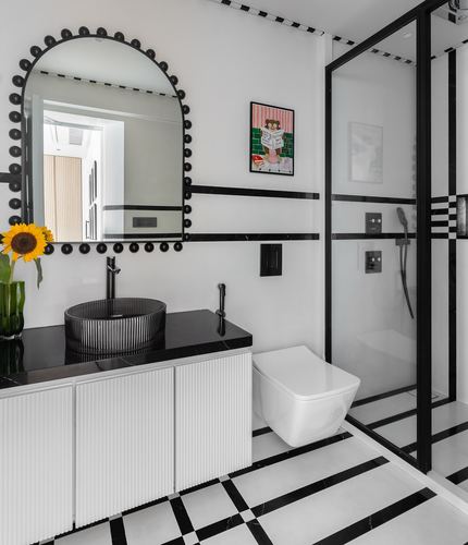 Black and white bathroom with arched scalloped mirror, fluted vanity, and checkered floor tiles
