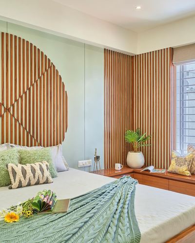 Bedroom with sage walls, wood slat headboard and window seat, knit throw on bed
