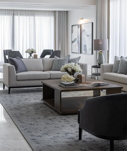 Neutral living room with two beige sofas, dark wood coffee table, patterned rug, and sheer curtained windows