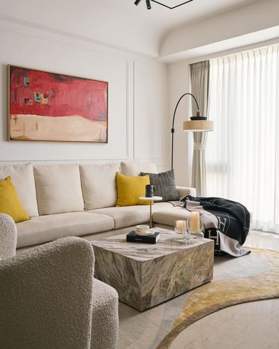 Neutral living room with beige sectional, mustard cushions, marble-look coffee table, and red abstract art