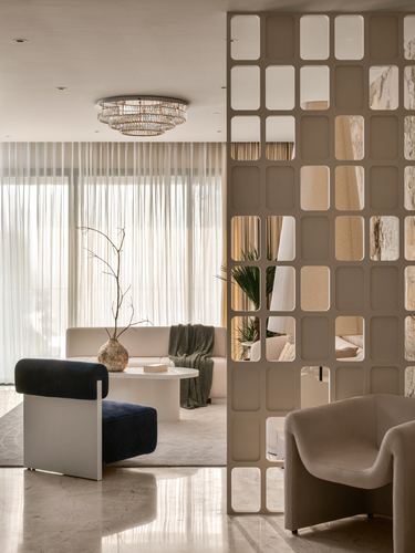 Living room with white sofa, marble table, and a mirrored fretwork screen dividing the space