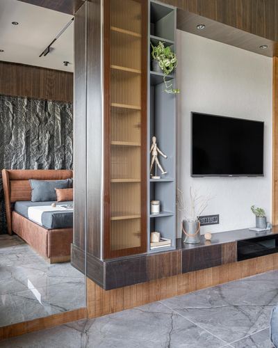 Bedroom with leather headboard beside a wood-fluted divider and TV console unit