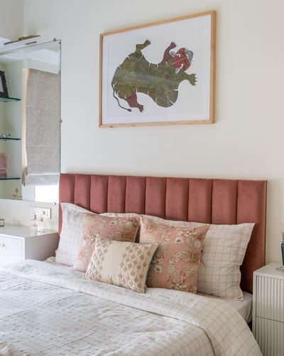 Bedroom with terracotta channel-tufted headboard, layered floral cushions, and framed animal artwork above