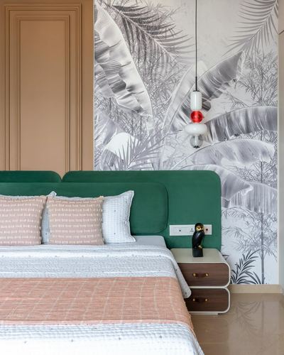 Bedroom with green velvet headboard, pink and white bedding, and a black and white palm leaf wallpaper wall