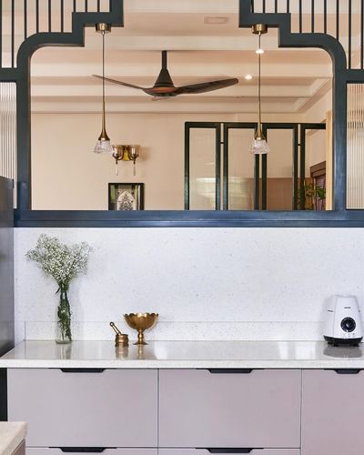 Kitchen counter with terrazzo backsplash seen through an arched dark-framed opening into living room