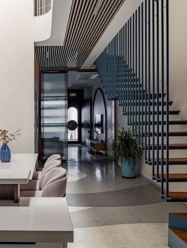 Terrazzo-floored entry hall with blue slatted staircase, arched mirror console, and dining area in foreground