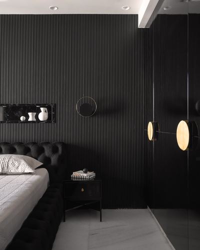 Dark fluted bedroom wall with tufted headboard, round mirror, and brass disc sconces