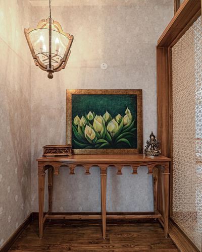 Wooden console table with framed lotus painting and lantern pendant in a foyer corner