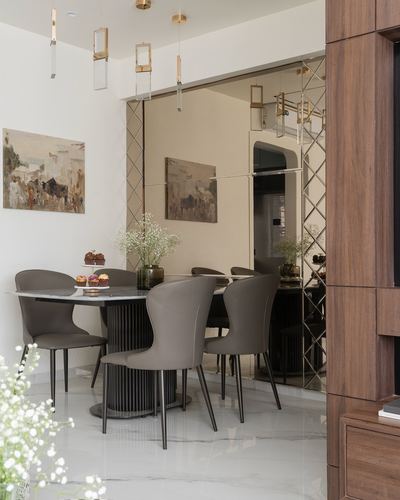 Dining room with marble-top table, taupe leather chairs, ribbed black pedestal legs, and mirrored diamond wall panel