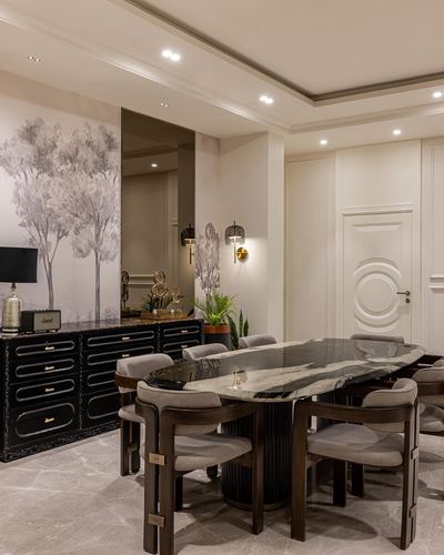 Elegant dining room with oval marble table, fluted base, and black sideboard beneath tree mural