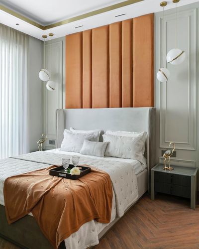 Bedroom with terracotta velvet panel wall, grey upholstered bed, and paired globe pendant lights