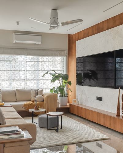Living room with marble and wood TV wall, beige sofas, and floral roman blinds