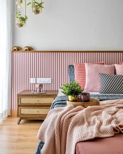 Bedroom with pink fluted headboard wall, cane nightstand, and pink knit throw on bed