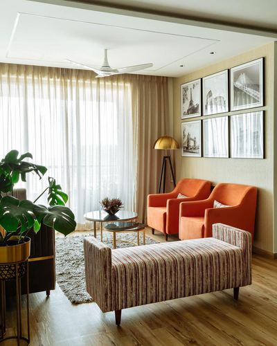 Living room with orange velvet chairs, striped bench, gallery wall and sheer-curtained balcony