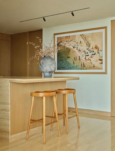Wood-toned kitchen island with two stools beneath a large framed beach photograph