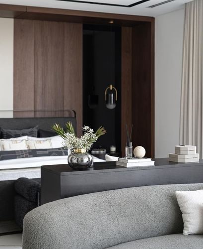 Dark wood-panelled bedroom seen past a boucle sofa and black console styled with vase and books