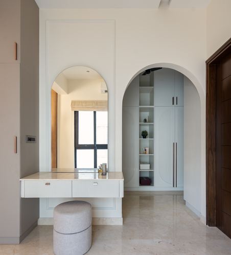 Dressing area with arched mirror niche and matching arched wardrobe alcove in soft palette