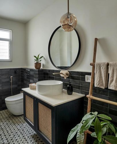 Bathroom with round black-framed mirror, amber pendant light, cane vanity and patterned floor tiles