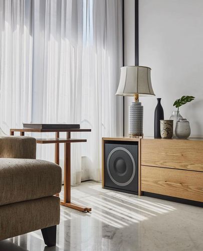 Wooden sideboard with lamp and vases beside sheer curtains and marble floor in sunlit living room