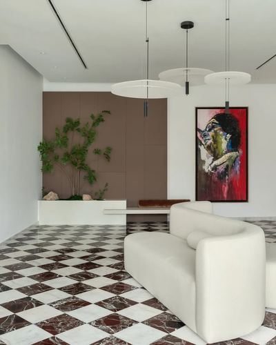 Curved white sofa on burgundy and white checkered marble floor beneath layered pendant lights and a colorful portrait painting