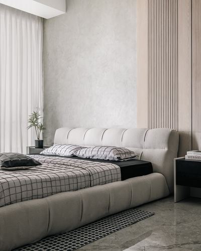 Beige tufted bed with checkered linens against a fluted wood and plaster wall bedroom
