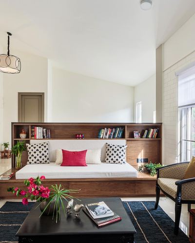 Living room with wooden daybed and bookshelf headboard, cane armchair, and dark rug