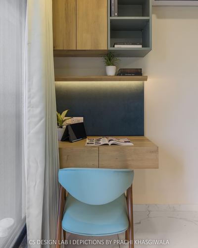 Small study nook with floating wood desk, backlit blue panel, and teal chair