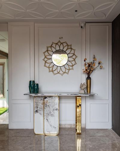Foyer with sunburst mirror above a marble and brass console table against paneled wall