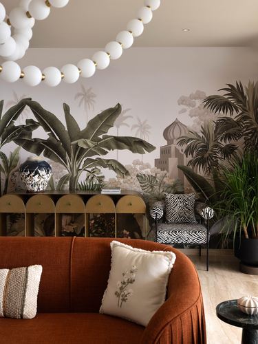 Living room with terracotta sofa, zebra armchair, arched brass cabinet and tropical mural wallpaper