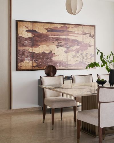 Dining room with marble table, cane-toned artwork panel, and pendant light in Mumbai home