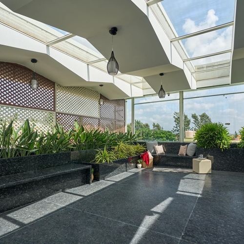 Rooftop terrace lounge with granite benches, planters, and folded glass skylight roof.