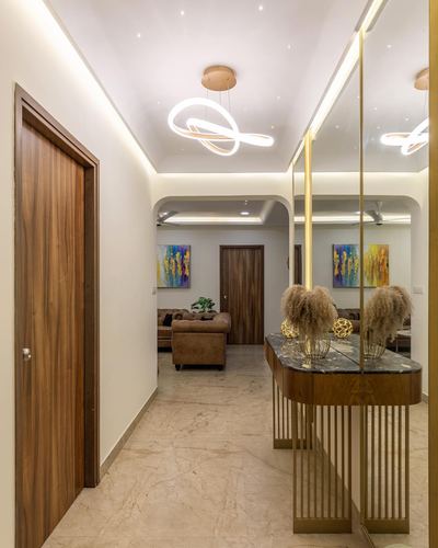 Foyer with mirrored wall, marble-top console on fluted brass legs, and sculptural pendant light