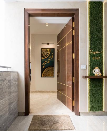 Entrance foyer with wooden pivot door, marble flooring, and green moss wall with nameplate
