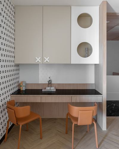 Built-in study nook with circular cabinet cutouts, black countertop, and orange leather chairs