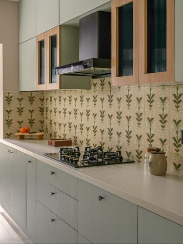 Sage green kitchen with floral tile backsplash, black hob, and reeded wood cabinet doors