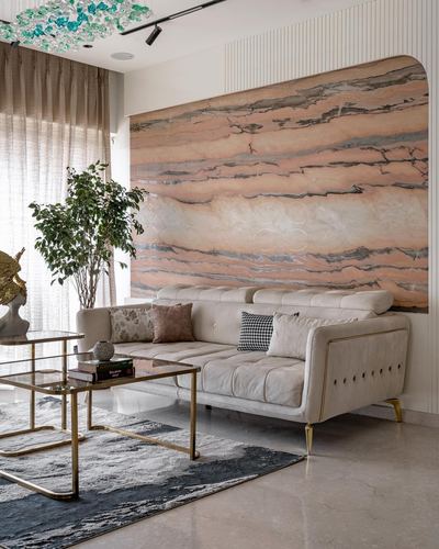 Living room with arched pink-veined marble wall behind a tufted beige sofa and brass coffee table