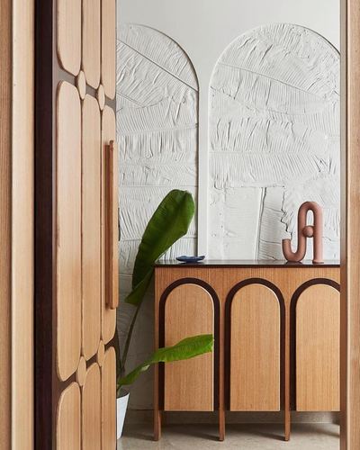 View through carved wooden door into foyer with textured plaster arches and wood console