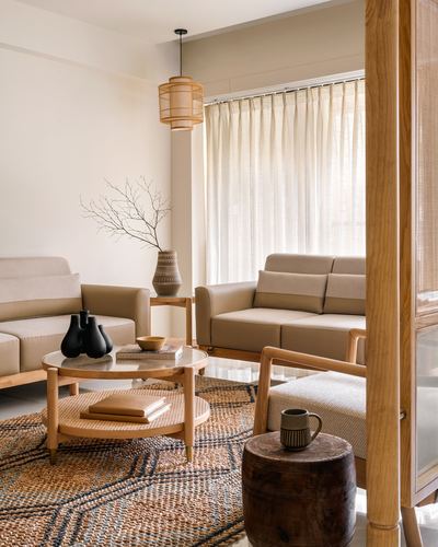 Japandi-style living room with wooden furniture, cane pendant light, and jute rug near sheer-curtained window