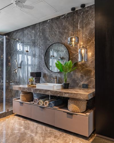 Bathroom vanity with marble slab, round mirror, pendant lights, and rattan baskets